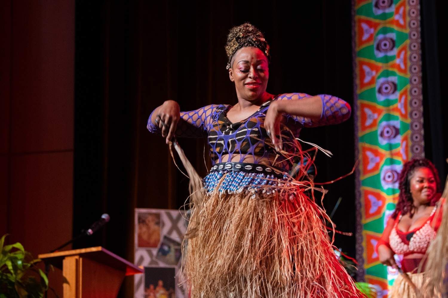 Woman in traditional African attire dancing on stage.
