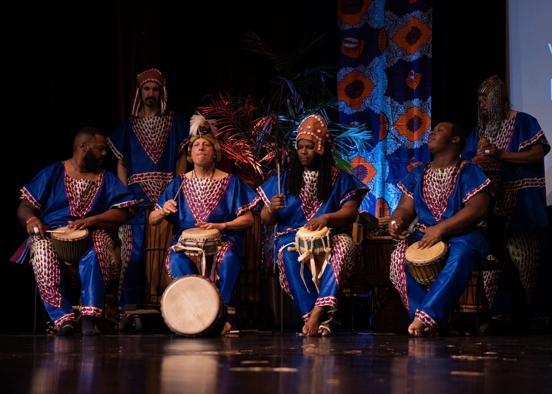 Drummers in blue and pink outfits performing on stage.