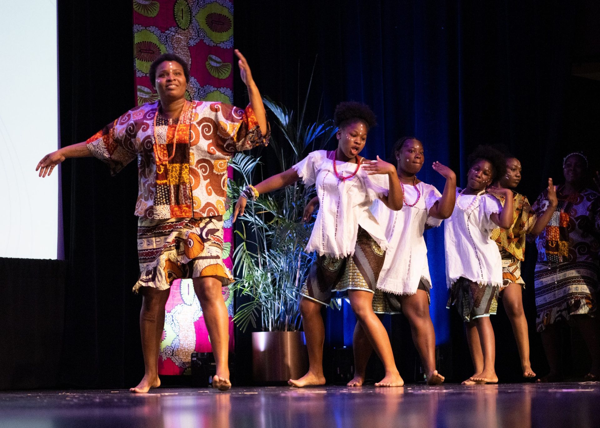 Group of Black women dancers in colorful outfits performing on stage.