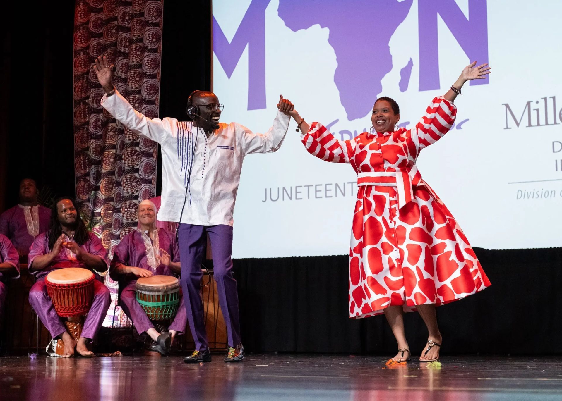 Man and woman dancing joyfully on stage, celebrating Juneteenth.