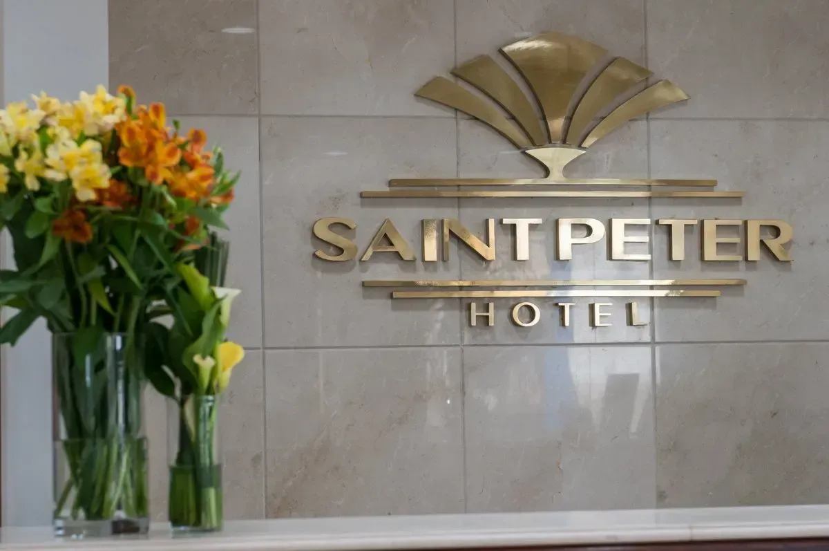 Uma placa para o hotel saint peter com flores na frente