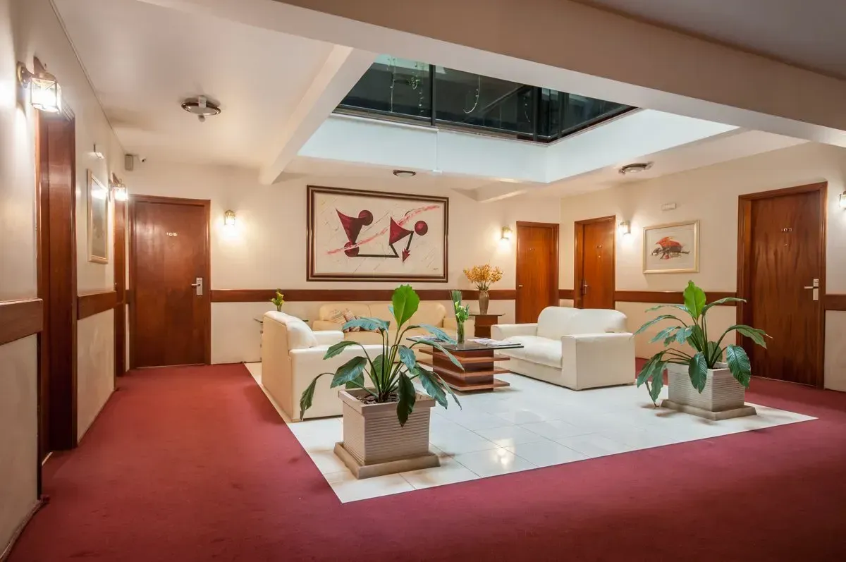 Um corredor com um sofá, cadeira, mesa e vasos de plantas.