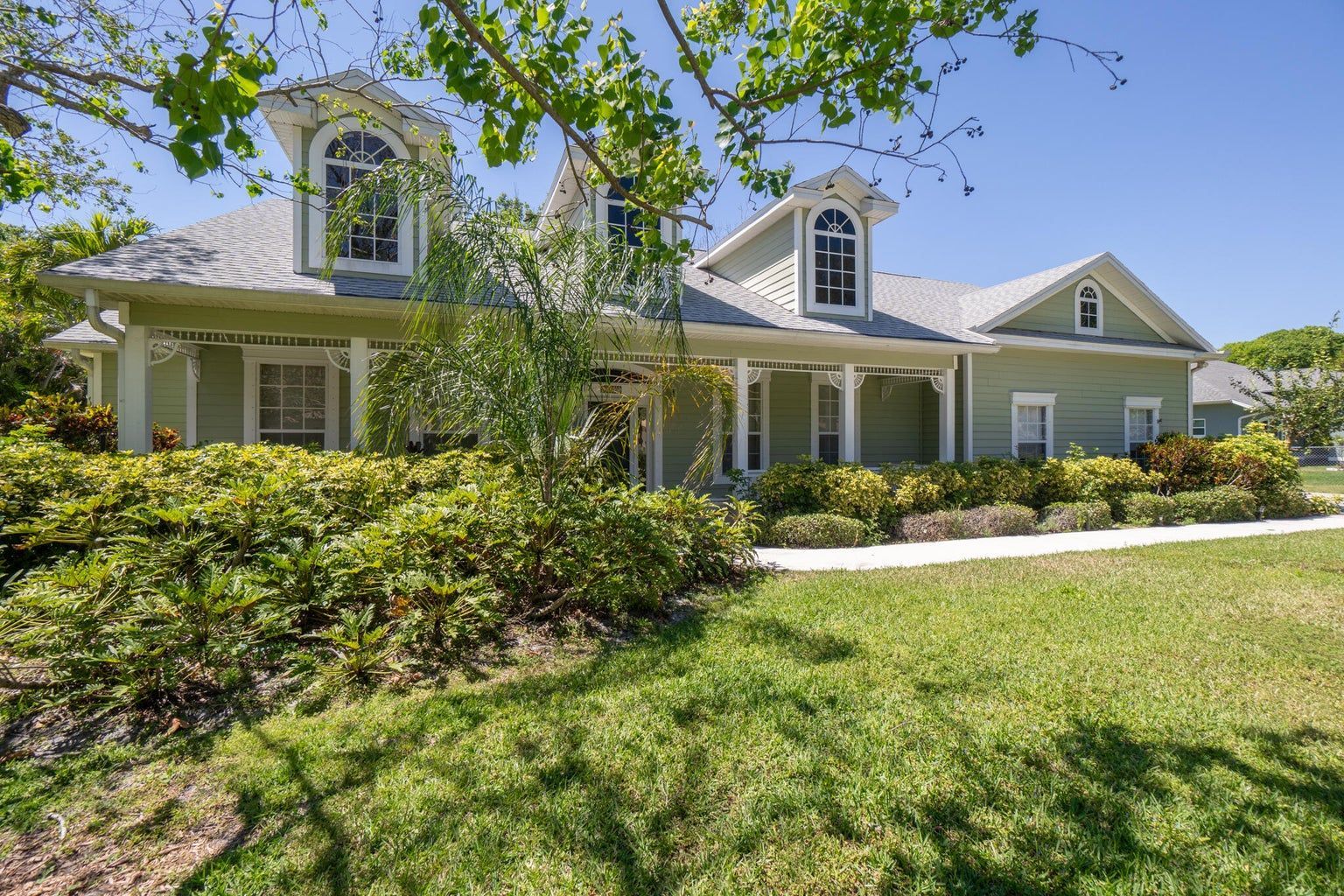 White house with brown roof and green lawn, blue sky.
