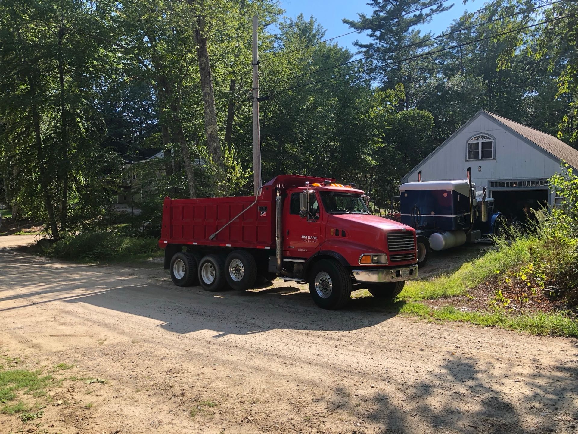 Red dump truck loaded with material parked on dirt