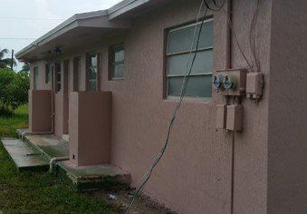 A pink house with a lot of wires hanging from the side of it.