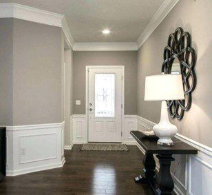 A hallway with a table , lamp and mirror.