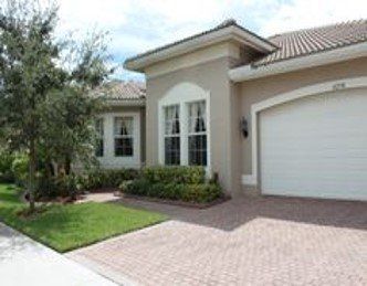 A large house with a white garage door and a brick driveway.