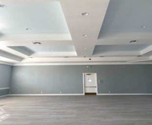 A large empty room with a ceiling that is very high and a door.