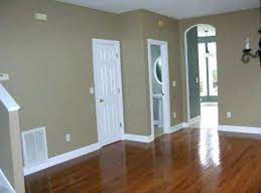 An empty living room with hardwood floors and tan walls.