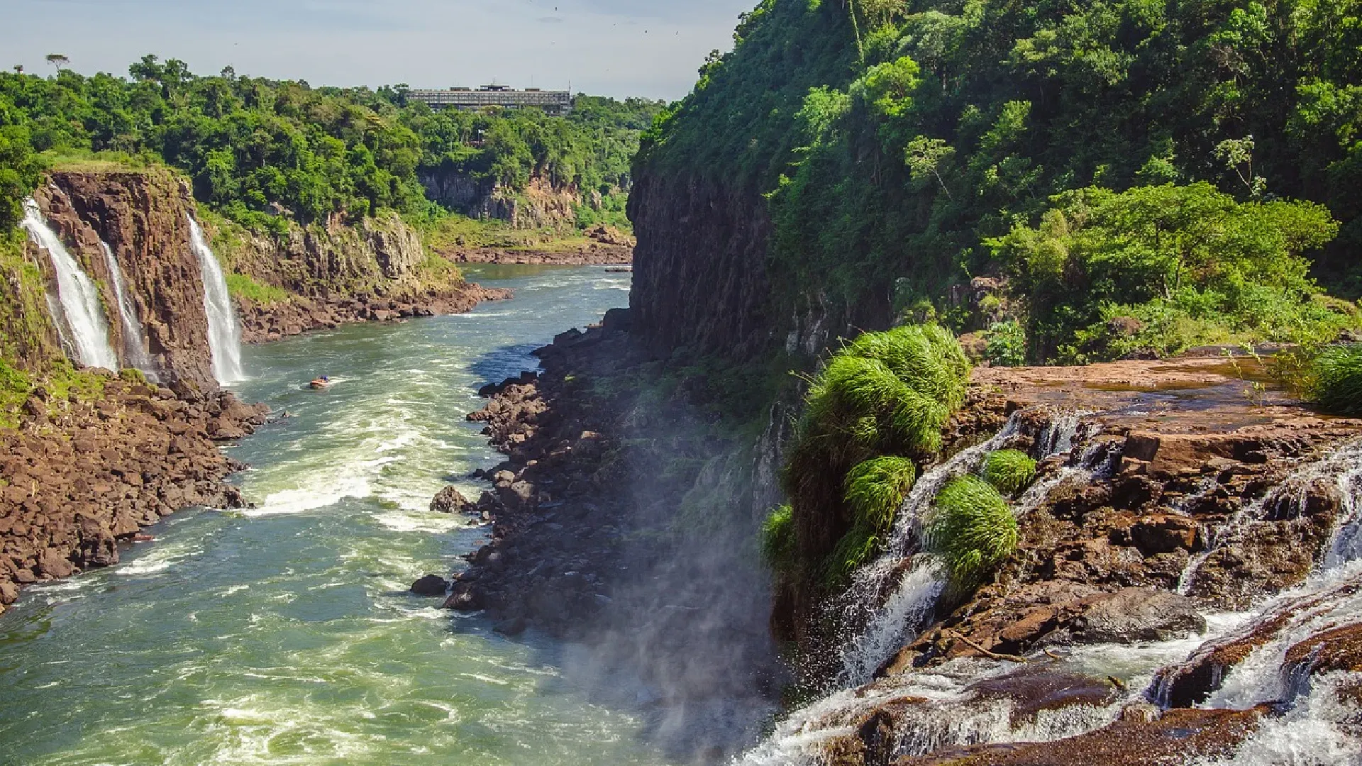 A waterfall is surrounded by trees and rocks in the middle of a river.