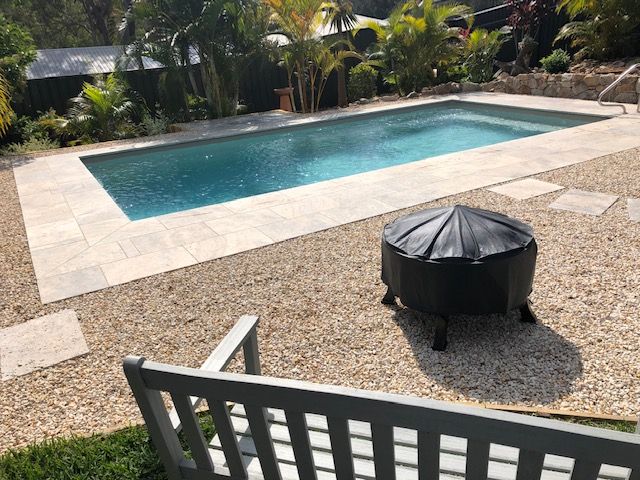 A Large Swimming Pool With a Fire Pit in the Backyard — Clarence Valley Pools In Woolgoolga, NSW
