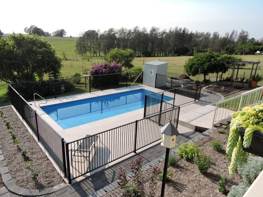 A Large Swimming Pool With a Fence Around It — Clarence Valley Pools In Woolgoolga, NSW