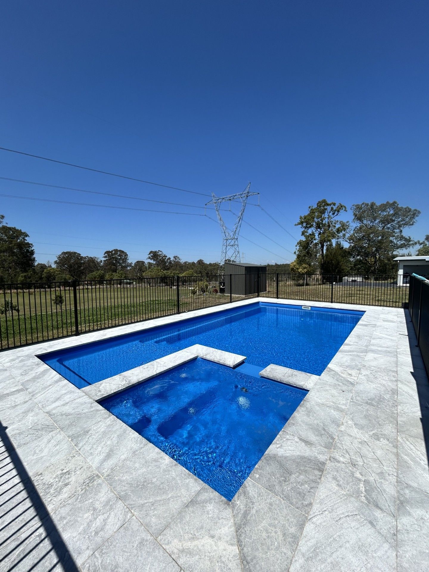 Blue rectangular swimming pool with integrated steps, surrounded by gray stone, under a clear sky — Clarence Valley Pools In Yamba, NSW
