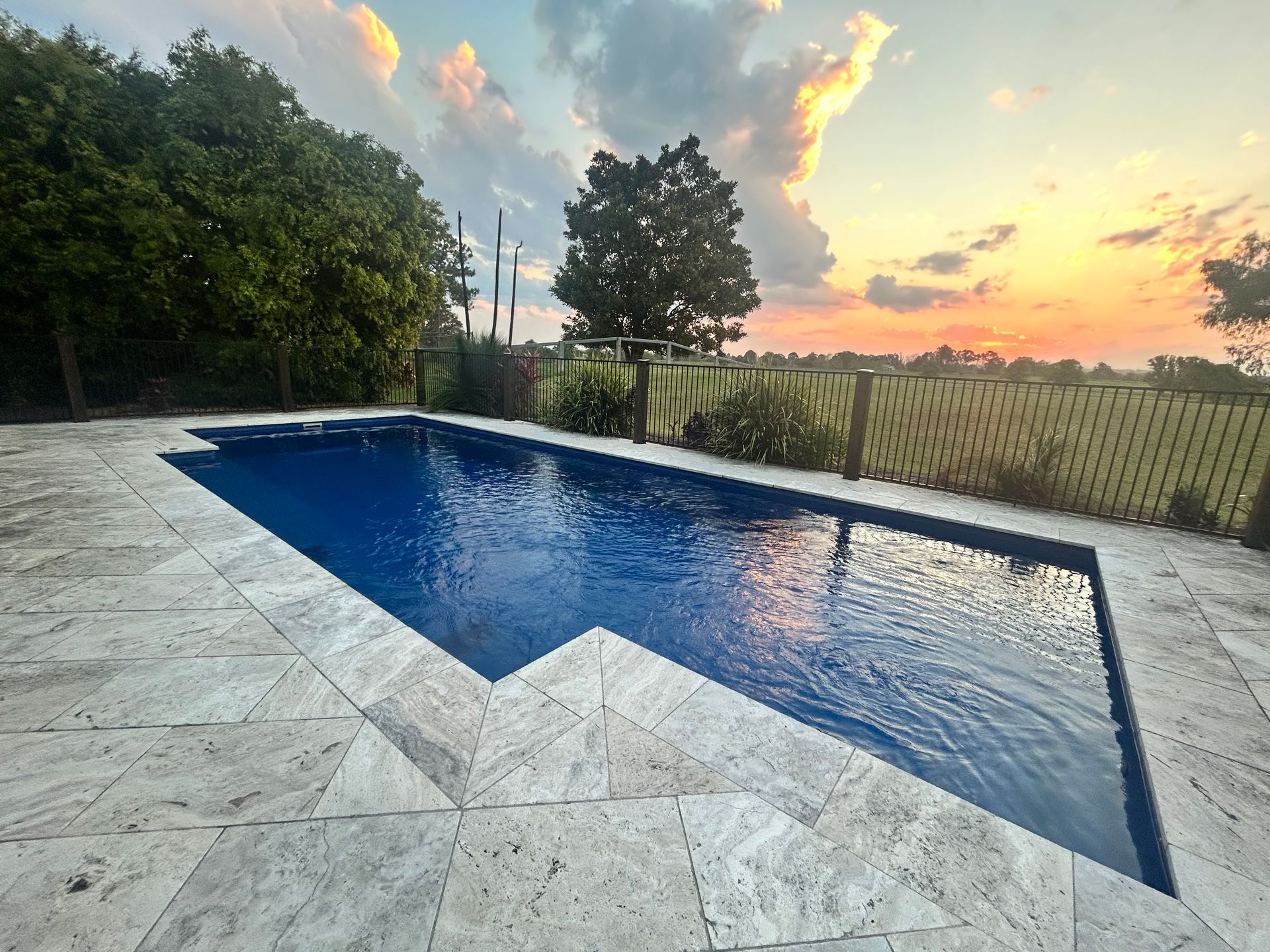 A Large Swimming Pool Surrounded by Chairs and a White Fence — Clarence Valley Pools In Coffs Harbour, NSW