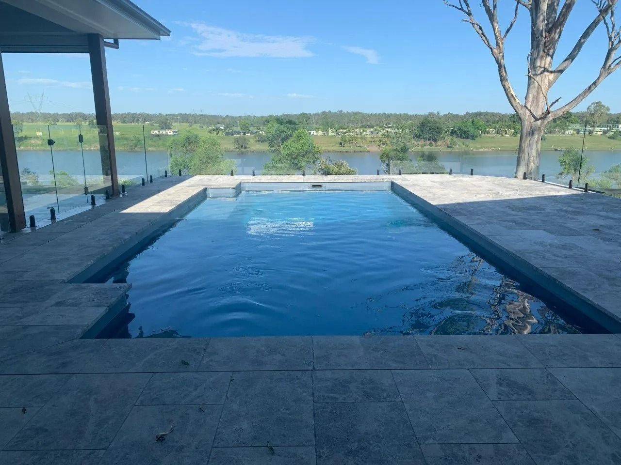 Swimming pool overlooking a body of water and trees, clear blue sky — Clarence Valley Pools In Yamba, NSW