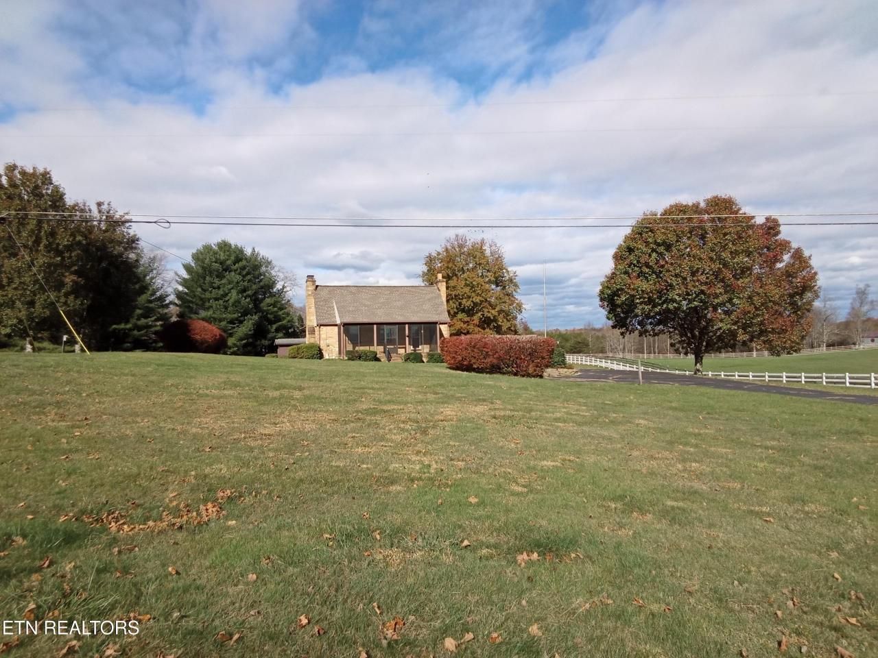 A small house sits in the middle of a grassy field