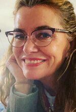 A close up of a woman wearing glasses and smiling.