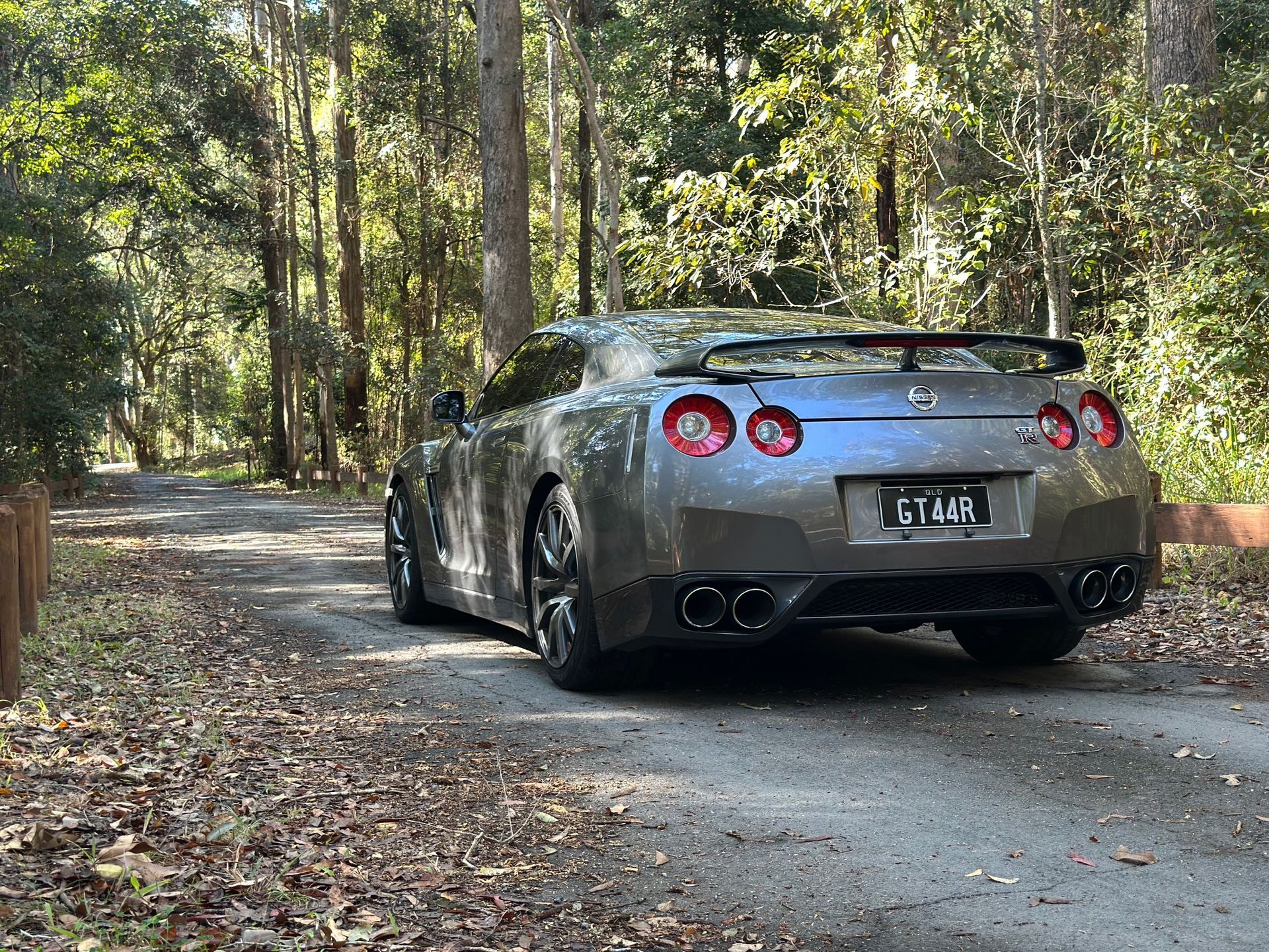 Gray GTR on road surrounded with trees — Car Hire in Mudgeeraba, QLD