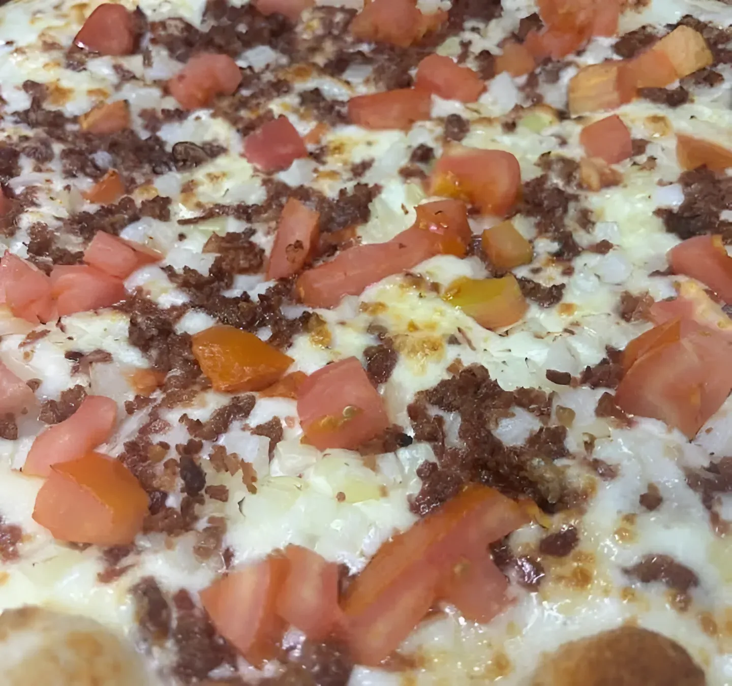 Pizza with tomatoes, bacon, ranch and onions.