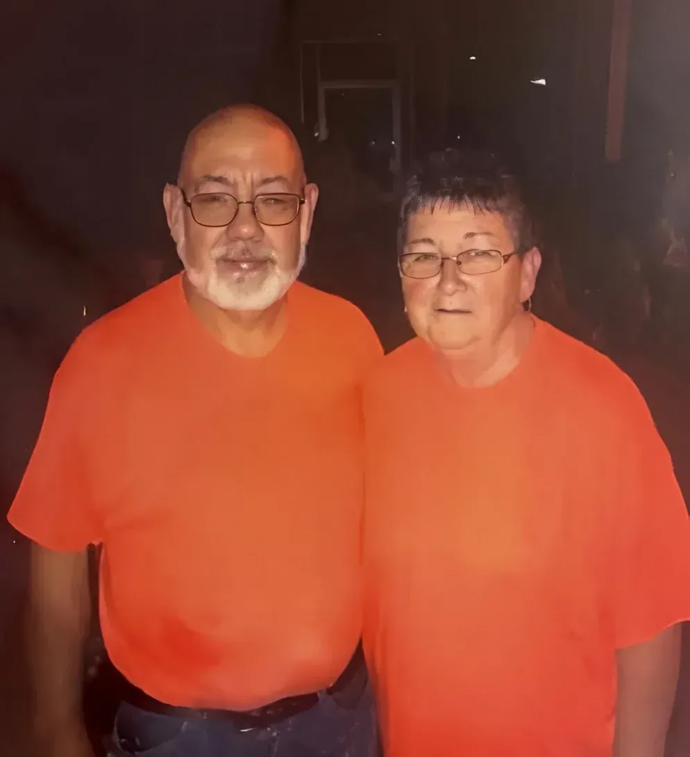Owners wearing orange shirts, standing close, looking at the camera.
