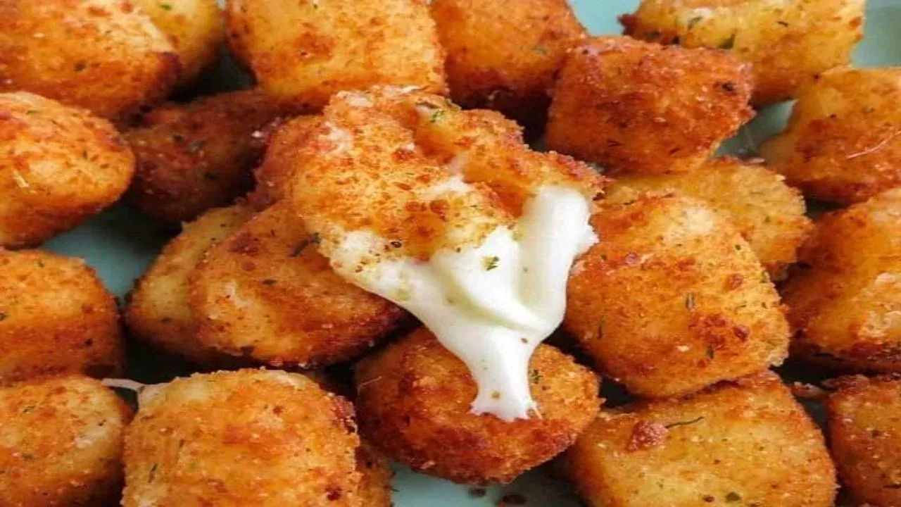 Golden-brown, fried cheese curds piled on a blue plate, one oozing melted cheese.