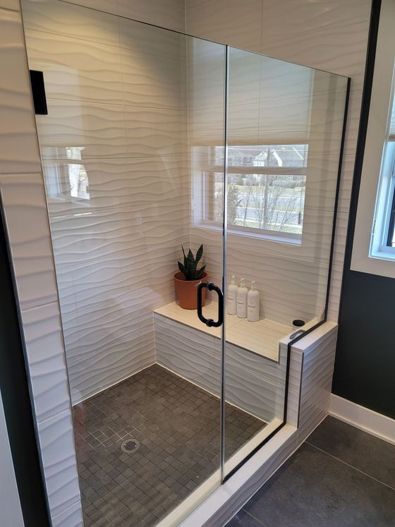 A bathroom with a glass shower door and a window.