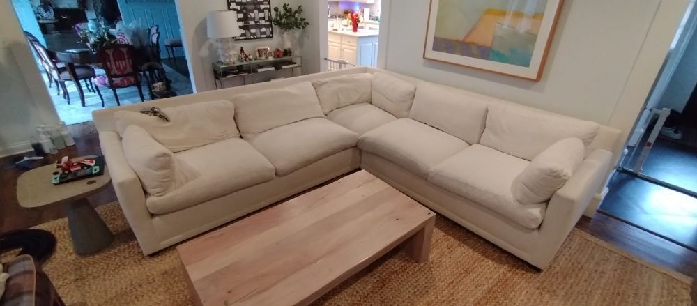 A living room with a white sectional couch and a wooden coffee table.