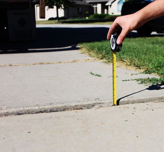 A person is measuring a sidewalk with a tape measure