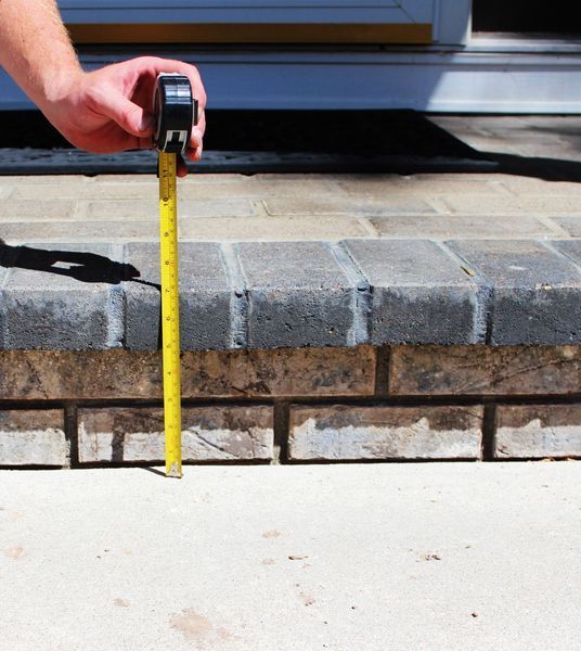 A person measuring a brick wall with a tape measure