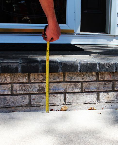 A person measuring a brick wall with a tape measure