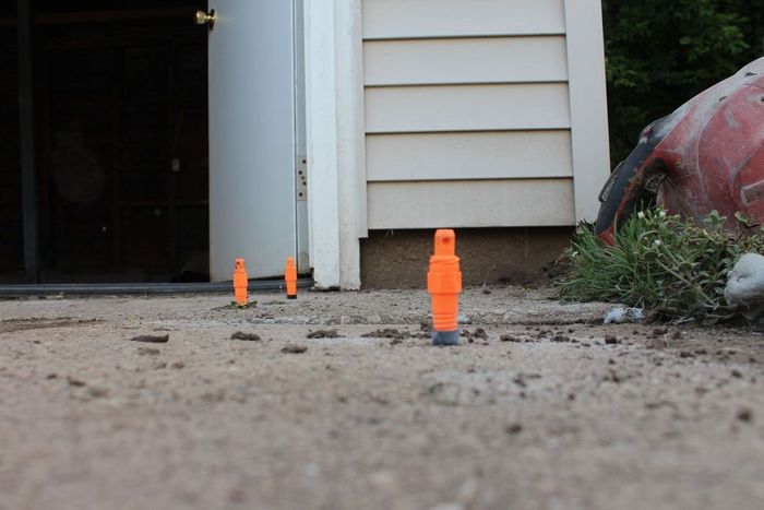 A bunch of orange cones are sitting on the ground in front of a house.