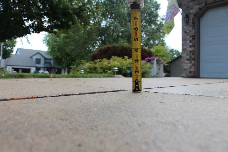 A yellow tape measure measures the height of a driveway