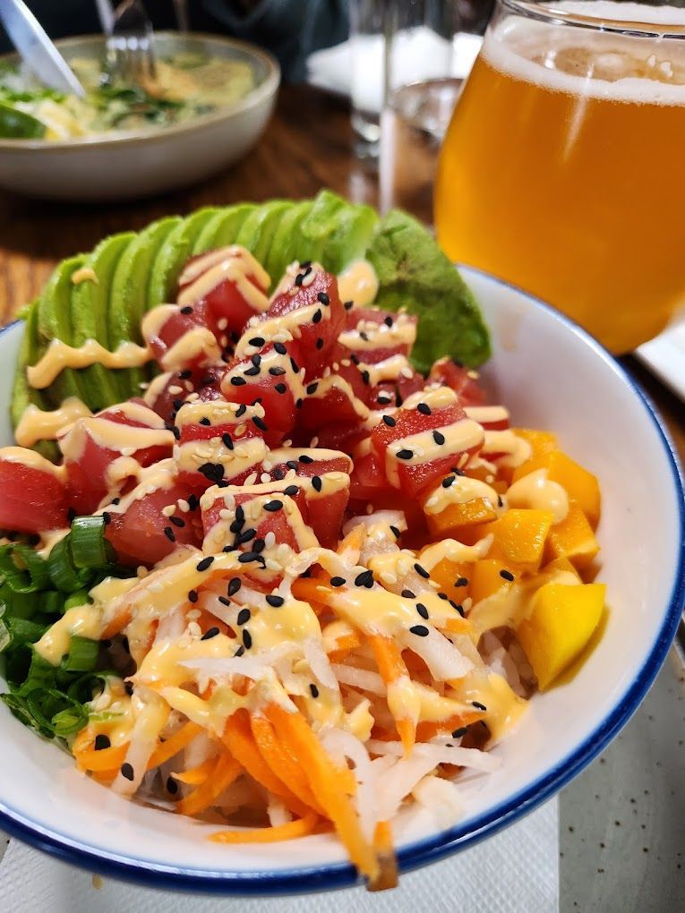A bowl of food with a glass of beer in the background