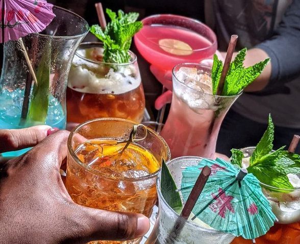 A group of people toasting with drinks and umbrellas