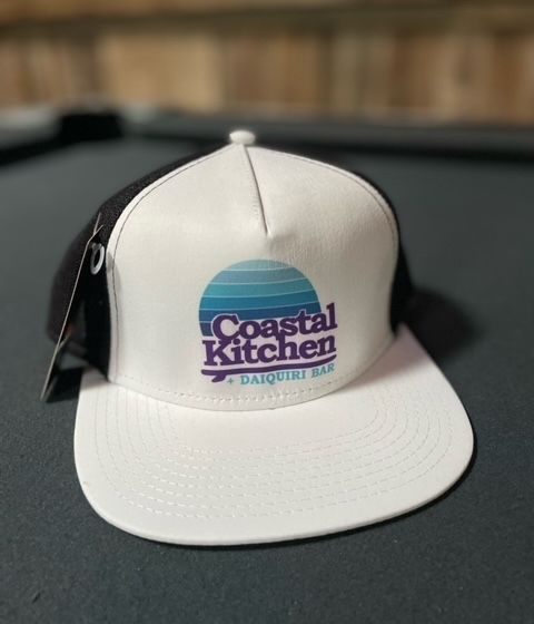 A white hat with the words coastal kitchen on it