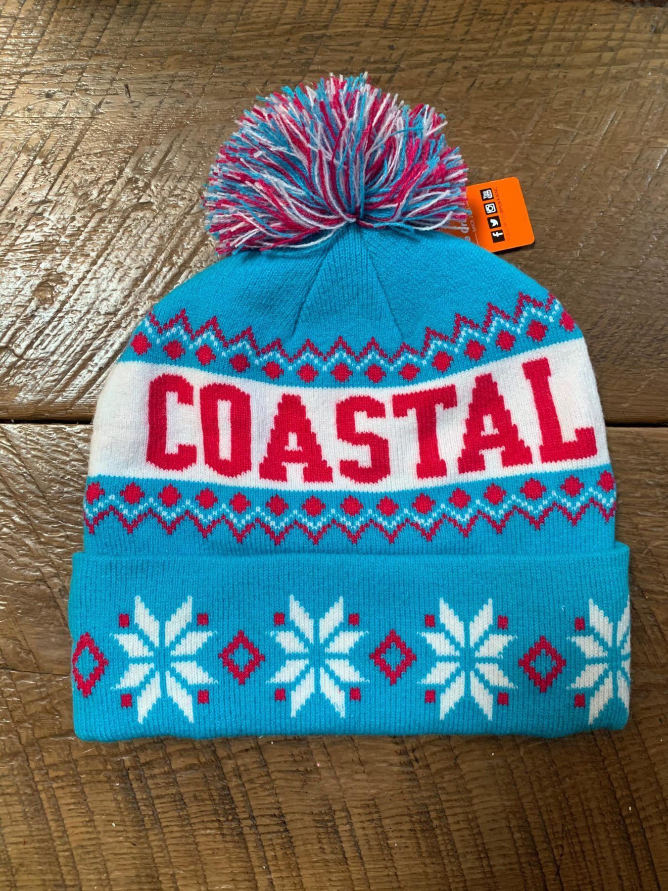 A blue beanie with the word coastal on it