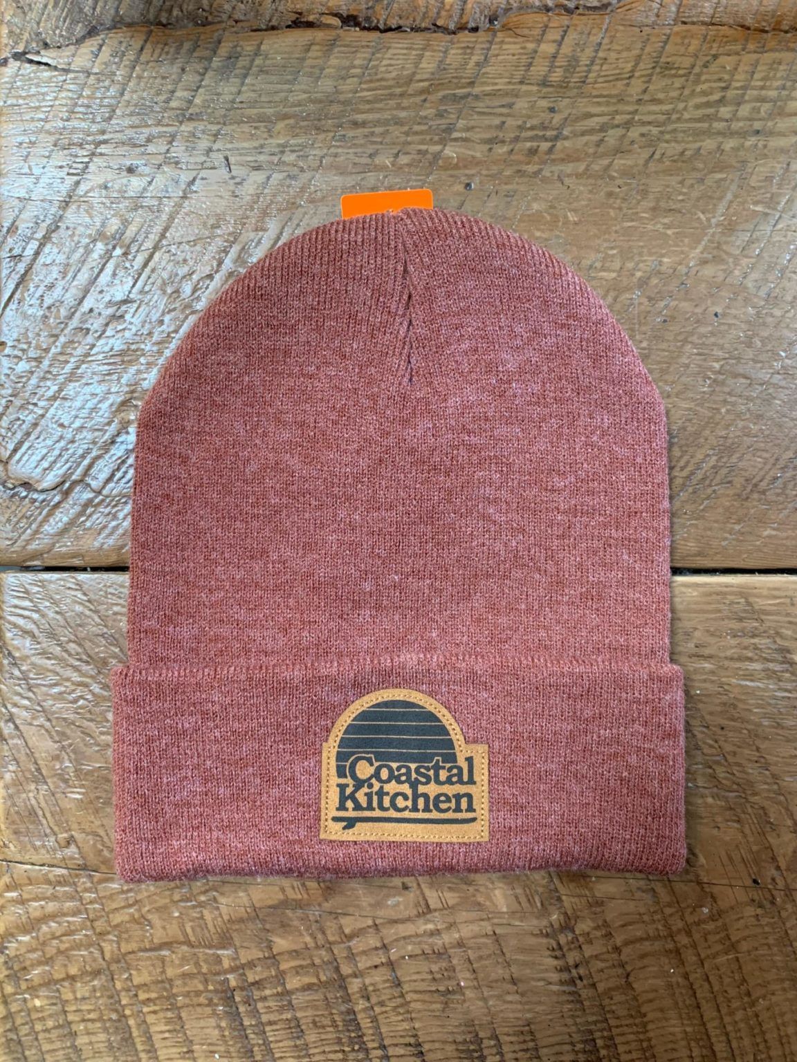 A pink beanie is sitting on top of a wooden table.