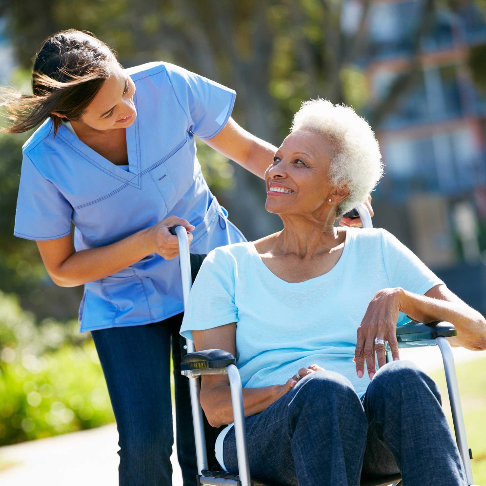 A nurse pushes an elderly woman in a wheelchair