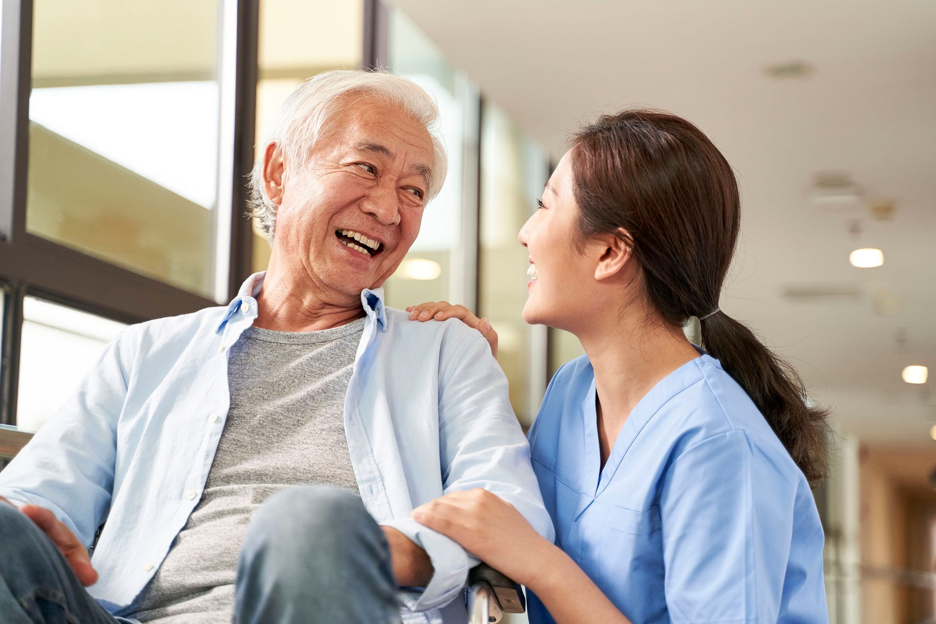 Twinlake nurse is talking to an elderly man in a wheelchair.