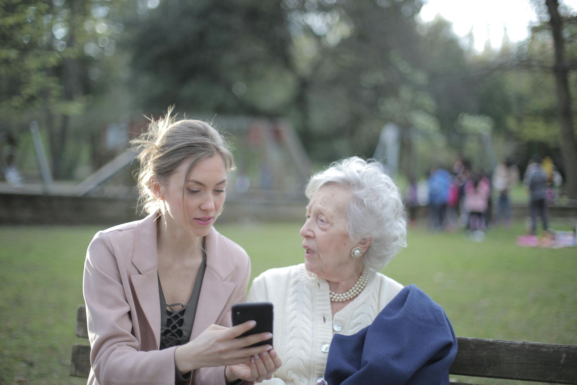 A nurse is holding the hands of an elderly woman and smiling.
