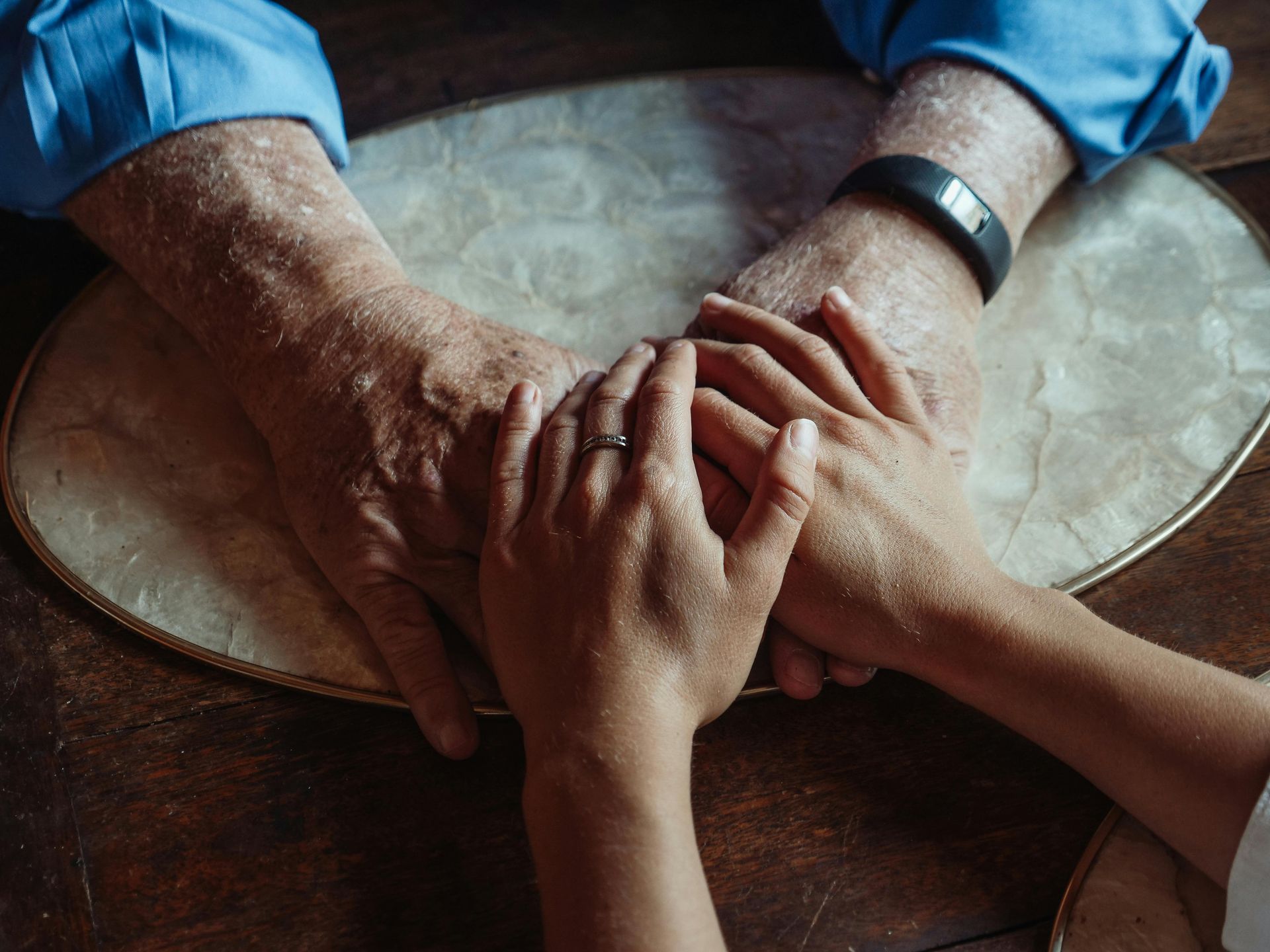 A woman is holding the hand of an elderly man in a wheelchair.