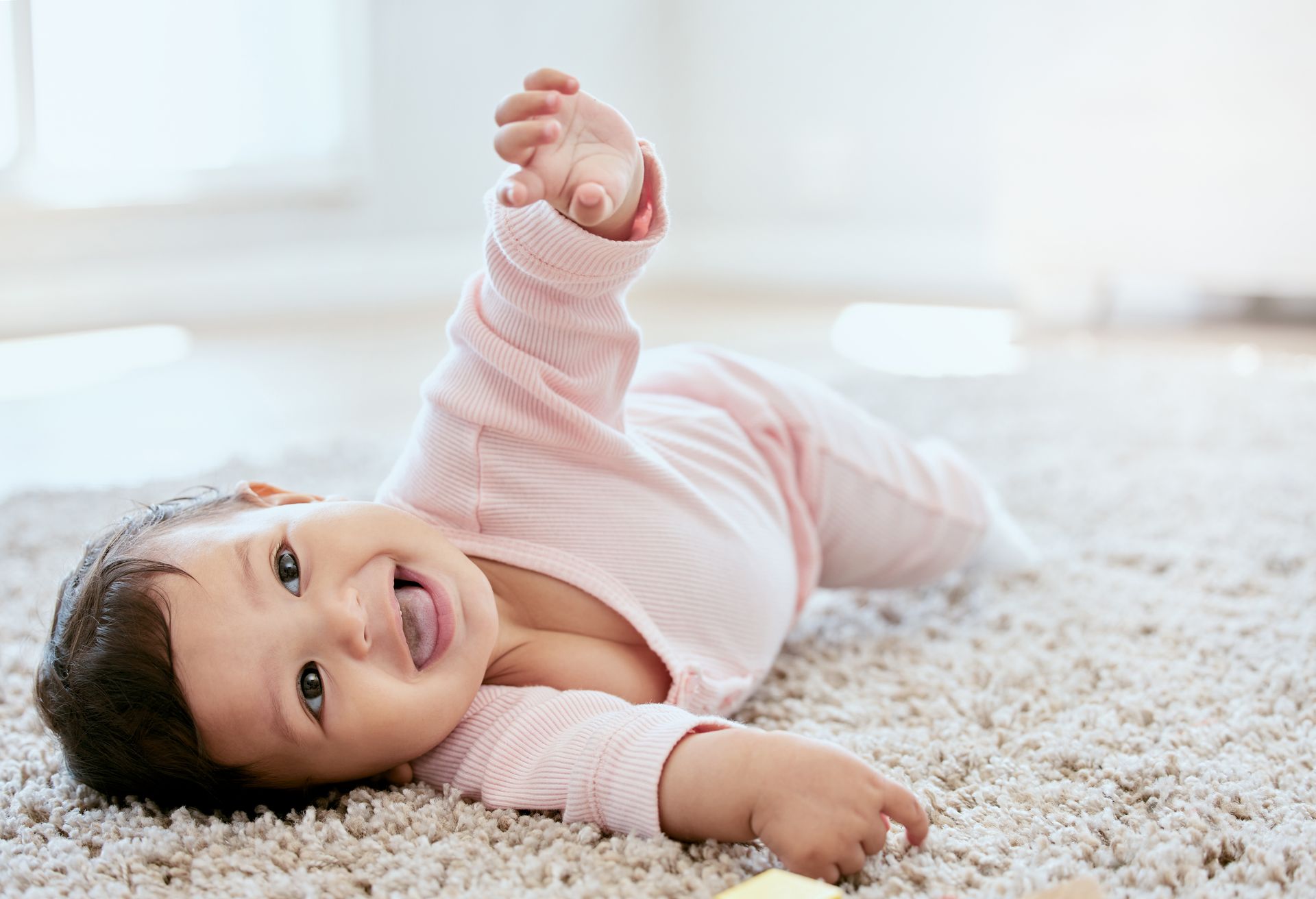 Sweet baby in pink rolling over on a rug