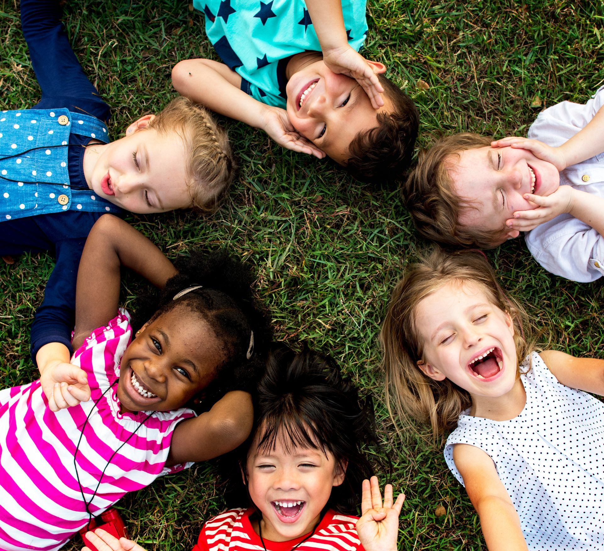 Circle of children laying in grass