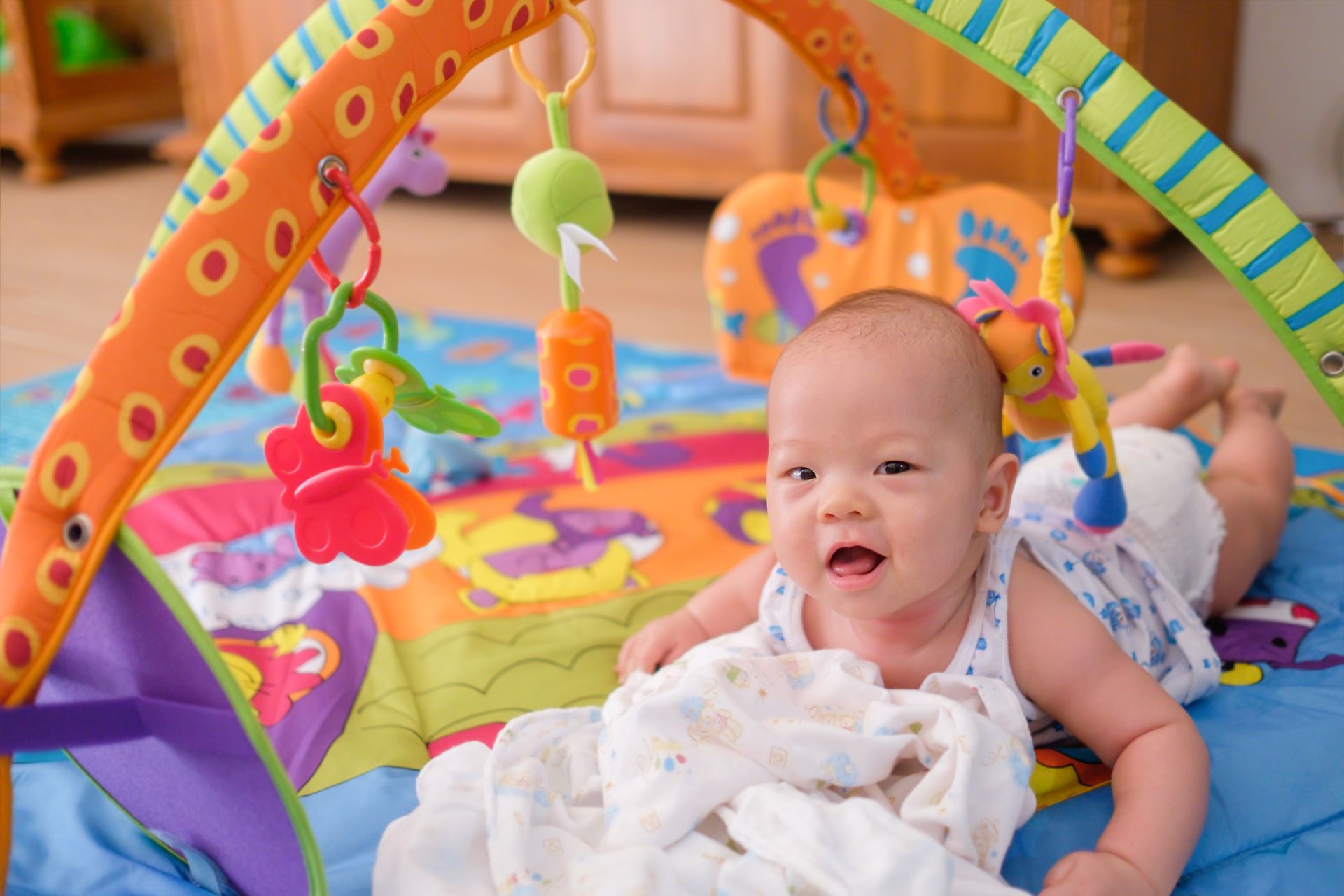 A baby is laying on a play mat with toys.