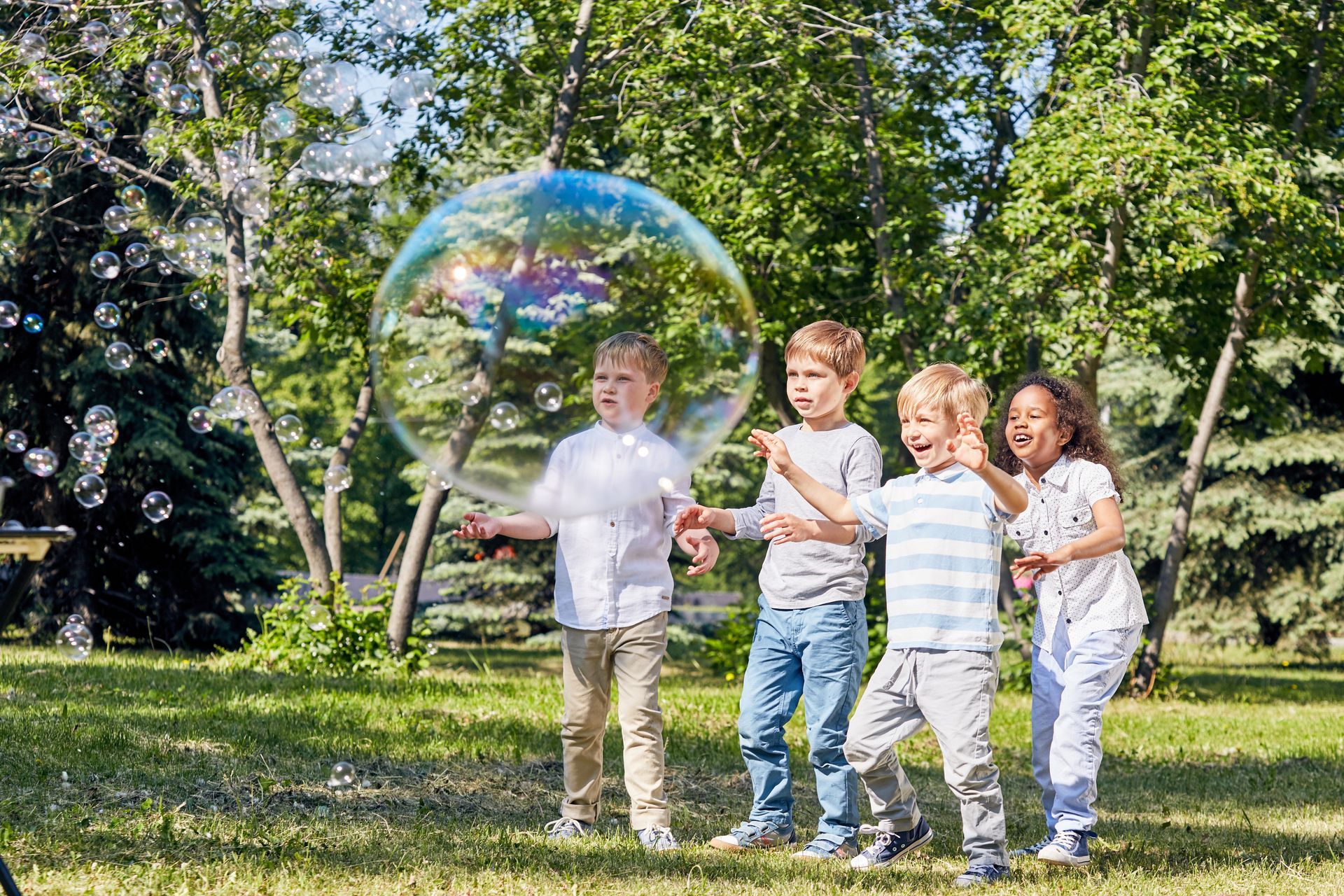 A group of children are playing with soap bubbles in a park.