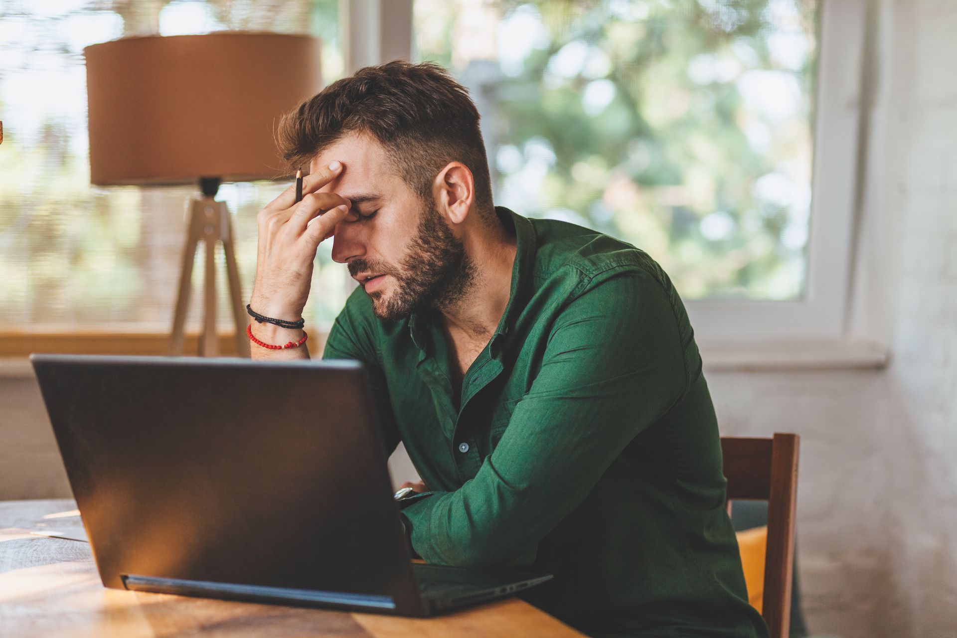 A man is sitting at a table using a laptop computer.