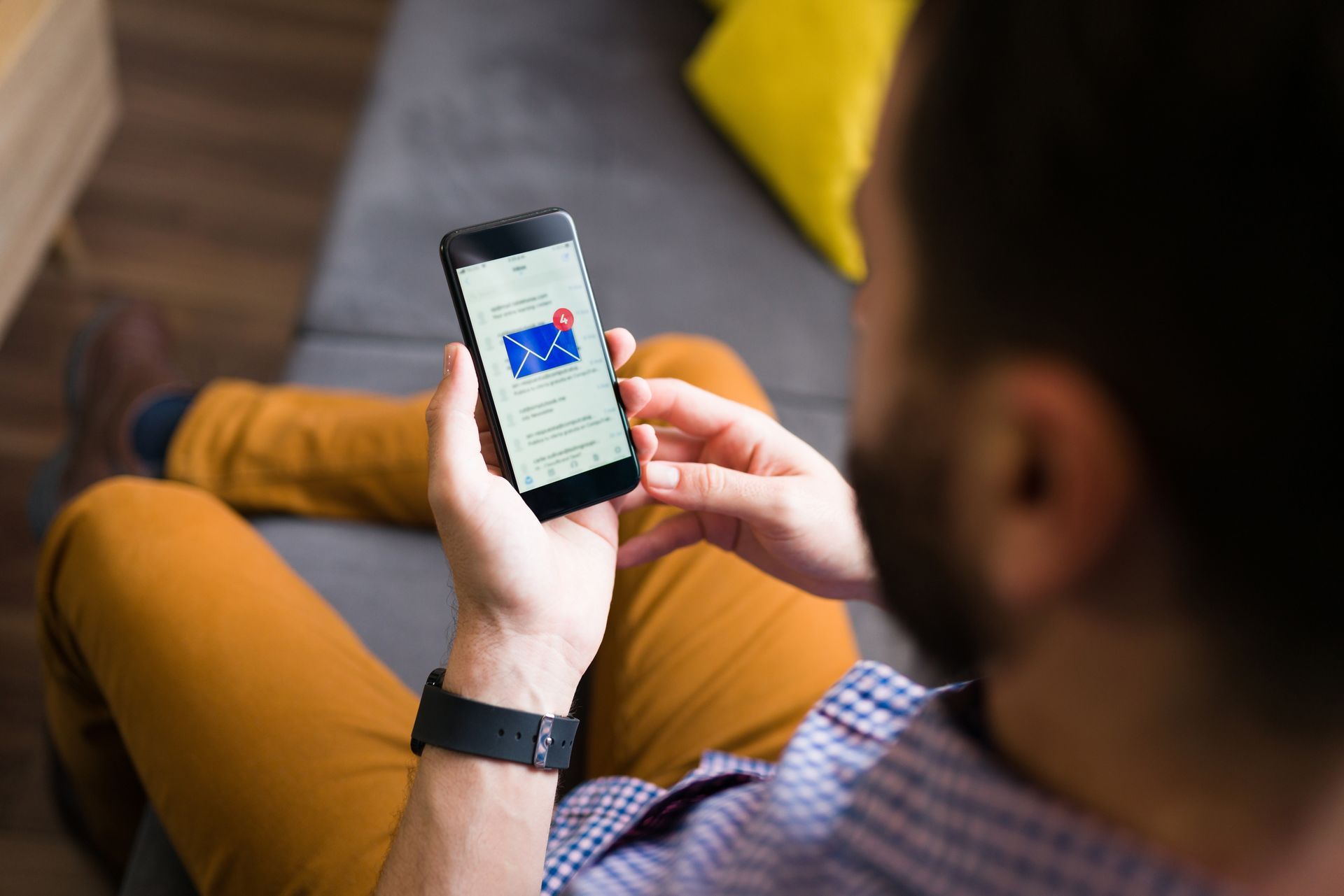 A man is sitting on a couch looking at his cell phone.