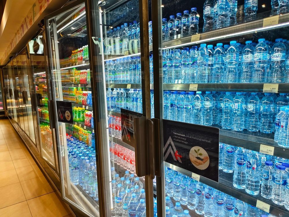 A refrigerator filled with lots of water bottles in a store.