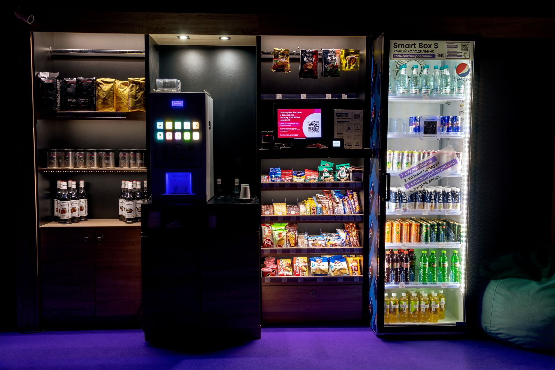Convenience store beverage coolers and snack shelves behind a central self-service kiosk, lit in blue and purple.
