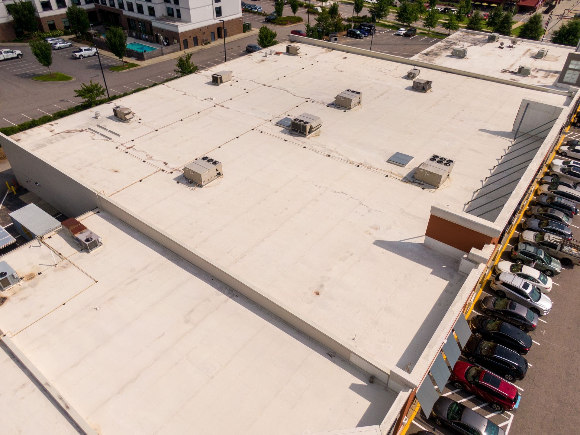 Aerial view of a large commercial building’s flat roof with multiple HVAC units and vents installed.